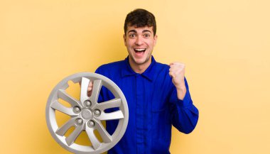 Genç yakışıklı adam şok olmuş hissediyor, gülüyor ve başarıyı kutluyor. araba tamircisi konsepti