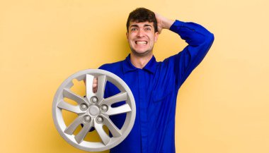 Genç ve yakışıklı bir adam stresli, endişeli ya da korkmuş hissediyor. Elleri başının üstünde. araba tamircisi konsepti