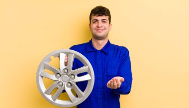 Genç ve yakışıklı bir adam arkadaşça gülümsüyor ve bir konsept sunuyor. araba tamircisi konsepti