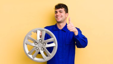 Genç ve yakışıklı bir adam gururlu, olumlu gülümsüyor. araba tamircisi konsepti