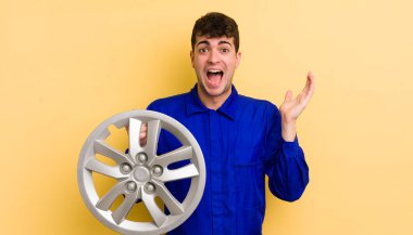 Genç yakışıklı adam kendini mutlu hissediyor ve inanılmaz bir şeye hayret ediyor. araba tamircisi konsepti