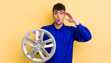 Genç yakışıklı adam mutlu, şaşkın ve şaşırmış görünüyor. araba tamircisi konsepti