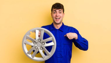 Genç ve yakışıklı bir adam mutlu hissediyor ve heyecanla kendini işaret ediyor. araba tamircisi konsepti