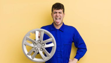 Genç, yakışıklı, neşeli ve asi tavırlı, şaka yapan ve dilini dışarı çıkaran bir adam. araba tamircisi konsepti