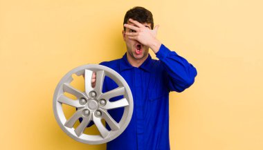 Genç, yakışıklı adam şok olmuş, korkmuş ya da korkmuş görünüyor. araba tamircisi konsepti