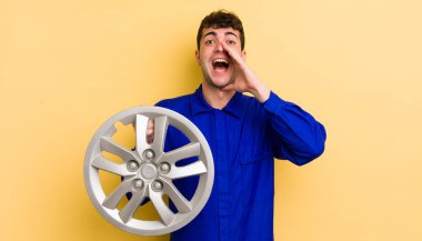 Genç yakışıklı adam mutlu hissediyor, elleri ağzının kenarında bağırıyor. araba tamircisi konsepti