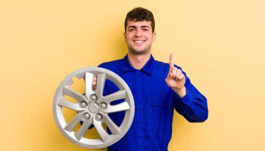 Genç yakışıklı adam gururla gülümsüyor ve kendinden emin bir numara oluyor. araba tamircisi konsepti