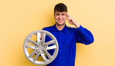 Genç yakışıklı adam kafası karışık ve şaşkın hissediyor, deli olduğunu gösteriyor. araba tamircisi konsepti