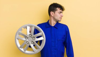 Profilde genç yakışıklı bir adam hayal kuruyor, hayal kuruyor ya da hayal kuruyor. araba tamircisi konsepti