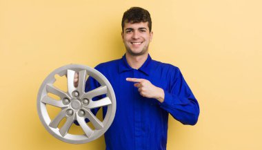 Genç yakışıklı adam neşeyle gülümsüyor, mutlu hissediyor ve bir tarafı işaret ediyor. araba tamircisi konsepti