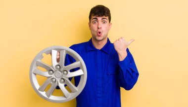 İnanamadığı için şaşırmış genç ve yakışıklı bir adam. araba tamircisi konsepti