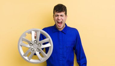 Genç yakışıklı adam agresif bir şekilde bağırıyor, çok kızgın görünüyor. araba tamircisi konsepti