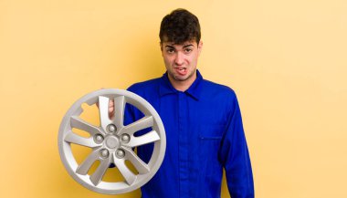 Genç yakışıklı adam şaşkın ve şaşkın hissediyor. araba tamircisi konsepti