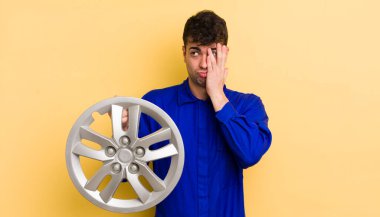 Genç yakışıklı bir adam bıkkın, hayal kırıklığına uğramış ve yorucu bir geceden sonra uykulu hissediyor. araba tamircisi konsepti