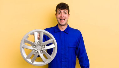 Genç yakışıklı adam mutlu ve hoş bir şekilde şaşırmış görünüyor. araba tamircisi konsepti