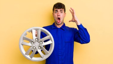 Genç yakışıklı adam ellerini havaya kaldırarak çığlık atıyor. araba tamircisi konsepti