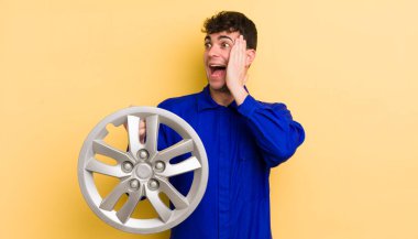 Genç yakışıklı adam mutlu, heyecanlı ve şaşırmış hissediyor. araba tamircisi konsepti