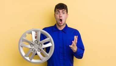 Genç ve yakışıklı bir adam şok olmuş ve şaşırmış hissediyor. araba tamircisi konsepti