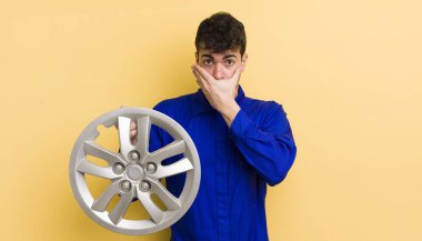 Genç ve yakışıklı bir adam elleri ile ağzını kapatıyor ve şok geçiriyor. araba tamircisi konsepti