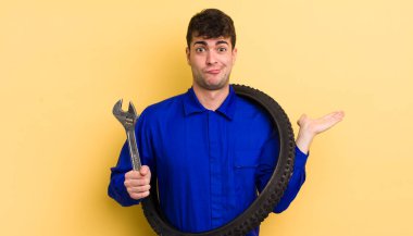 Genç yakışıklı adam şaşkın, şaşkın ve şüpheci hissediyor. motor tamircisi kavramı