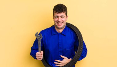 Genç yakışıklı bir adam komik bir şakaya yüksek sesle gülüyor. motor tamircisi kavramı