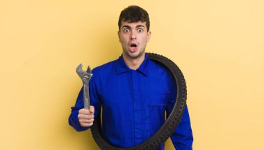 Genç ve yakışıklı bir adam çok şaşırmış ya da şaşkın görünüyor. motor tamircisi kavramı