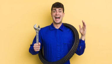 Genç yakışıklı adam kendini mutlu hissediyor ve inanılmaz bir şeye hayret ediyor. motor tamircisi kavramı