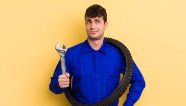 Genç yakışıklı adam omuz silkiyor, kafası karışık ve kararsız. motor tamircisi kavramı