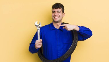 Genç yakışıklı adam neşeyle gülümsüyor, mutlu hissediyor ve bir tarafı işaret ediyor. motor tamircisi kavramı