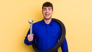 Genç yakışıklı adam mutlu ve hoş bir şekilde şaşırmış görünüyor. motor tamircisi kavramı