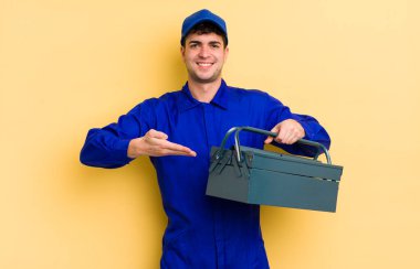 Genç yakışıklı adam neşeyle gülümsüyor, mutlu hissediyor ve bir konsept gösteriyor. tesisatçı kavramı