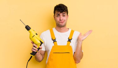 Genç yakışıklı adam şaşkın, şaşkın ve şüpheci hissediyor. Tamirci ve matkap konsepti