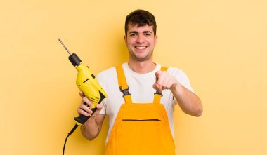 Genç ve yakışıklı bir adam kamerayı işaret ederek seni seçiyor. Tamirci ve matkap konsepti