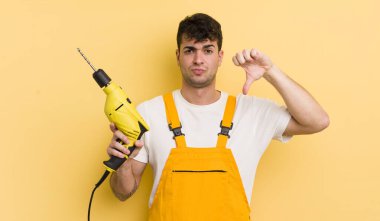 Genç ve yakışıklı bir adam kendini kötü hissediyor, baş parmağını kaldırıyor. Tamirci ve matkap konsepti