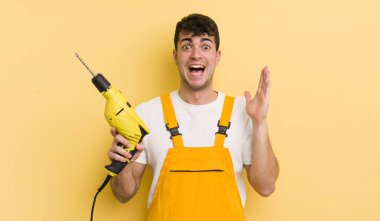 Genç yakışıklı adam kendini mutlu hissediyor ve inanılmaz bir şeye hayret ediyor. Tamirci ve matkap konsepti