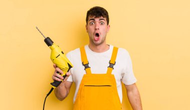 Genç ve yakışıklı bir adam çok şaşırmış ya da şaşkın görünüyor. Tamirci ve matkap konsepti