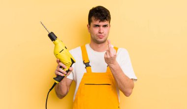 Genç ve yakışıklı bir adam sinirli, sinirli, asi ve agresif hissediyor. Tamirci ve matkap konsepti