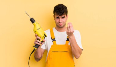 Genç yakışıklı adam kapiş ya da para hareketi yapıyor, sana ödemeni söylüyor. Tamirci ve matkap konsepti