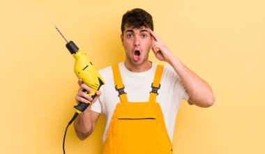 Genç yakışıklı adam şaşırmış görünüyor, yeni bir düşünce, fikir ya da konsept fark ediyor. Tamirci ve matkap konsepti