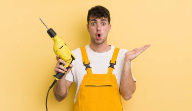 Genç, yakışıklı adam şaşırmış ve şok olmuş görünüyor. Çenesi düşmüş, elinde bir nesne var. Tamirci ve matkap konsepti