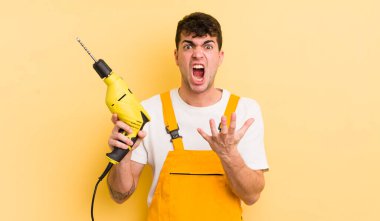 Genç yakışıklı adam umutsuz, sinirli ve stresli görünüyor. Tamirci ve matkap konsepti