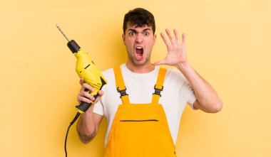 Genç yakışıklı adam ellerini havaya kaldırarak çığlık atıyor. Tamirci ve matkap konsepti