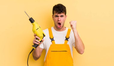 Genç yakışıklı adam sinirli bir ifadeyle agresif bir şekilde bağırıyor. Tamirci ve matkap konsepti