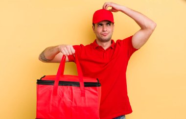 Kafası karışmış, kafası karışmış, kaşınan genç, yakışıklı bir adam. Pizza kurye konsepti