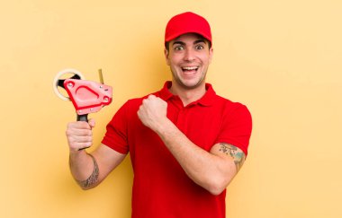 Genç yakışıklı adam kendini mutlu hissediyor ve bir meydan okumayla yüzleşiyor ya da kutluyor. paketleyici kavramı