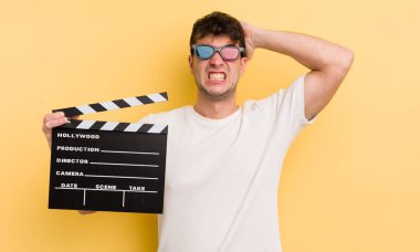 Genç ve yakışıklı bir adam stresli, endişeli ya da korkmuş hissediyor. Elleri başının üstünde. Sinema alkışlama konsepti