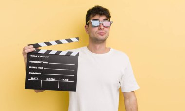 Genç yakışıklı adam omuz silkiyor, kafası karışık ve kararsız. Sinema alkışlama konsepti