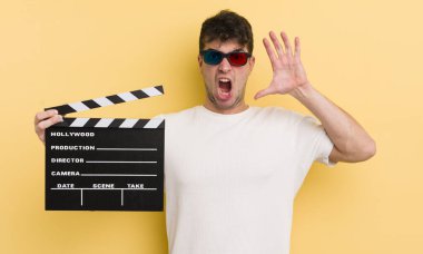 Genç yakışıklı adam ellerini havaya kaldırarak çığlık atıyor. Sinema alkışlama konsepti