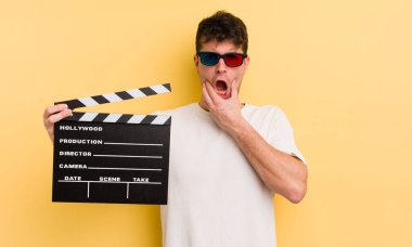 Ağzı ve gözleri açık ve eli çenesinde genç yakışıklı bir adam. Sinema alkışlama konsepti