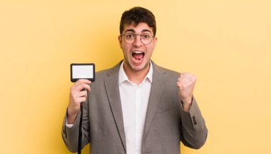 Genç yakışıklı adam şok olmuş hissediyor, gülüyor ve başarıyı kutluyor. VIP geçiş konsepti